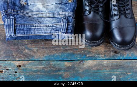 Blue jeans and work boots. Pants on old boards. Black leather shoes. Stock Photo