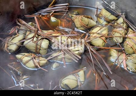 A bunch of rice dumplings, zongzi, cooking in water. Zongzi is a traditional Chinese rice dish made of glutinous rice stuffed with different fillings Stock Photo