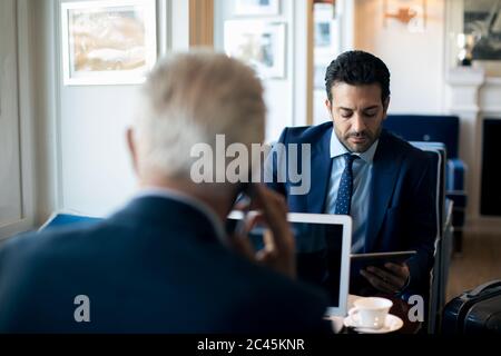Two businessmen sitting indoors, talking. Stock Photo