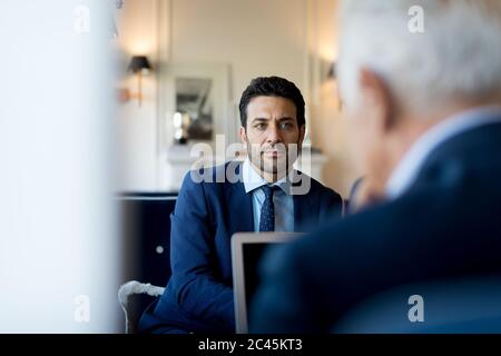 Two businessmen sitting indoors, talking. Stock Photo