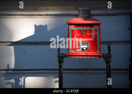 Red old-time post box and it's shadow on the wall Stock Photo