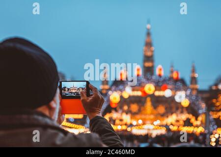 Man taking photo of Christmas market at Vienna City Hall in blue hour light Stock Photo