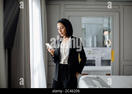 Businesswoman using smartphone in suite Stock Photo