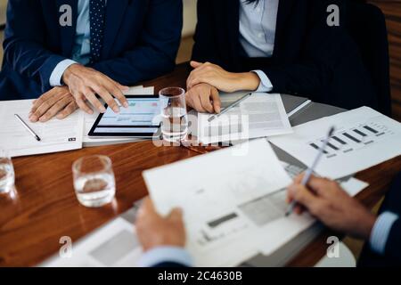 Businessmen and woman at boardroom table using digital tablet and working on paperwork, cropped Stock Photo