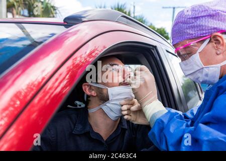 A doctor in a protective suit taking a nasal swab from a person to test for possible coronavirus infection Stock Photo