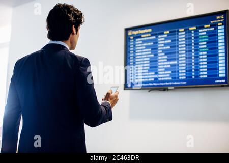 Businessman checking departure board Stock Photo