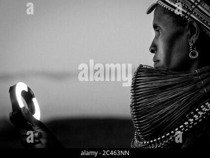 Rendille tribeswoman wearing traditional headdress and mpooro engorio necklace looking a ring flash, Marsabit district, Ngurunit, Kenya Stock Photo