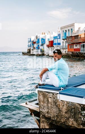 young guy on vacation at the Greek Island of Mykonos, men relaxing at the little venice village of Mykonos Island Stock Photo