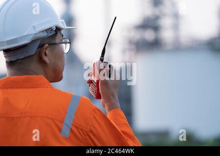 Male engineer workers on walkie-talkie outside the refinery. Stock Photo