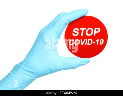 Woman hand in medical gloves holds red sign Stop Covid-19 on white background Stock Photo