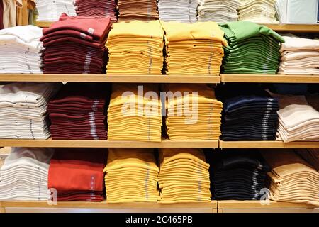 Colored T-shirts in stacks on a shelf. Stock Photo