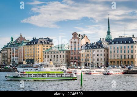 Hop on-Hop of tourist boat for sightseeing in the background of the historic buildings of Gamla Stan (Old Town Stockholm). Stock Photo