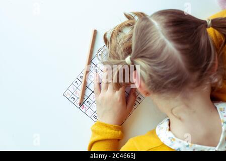 TIred teen girl solving sudoku at desk at school or at home. View from above Stock Photo