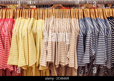Close-up of multi-colored striped t-shirts on hangers. Stock Photo