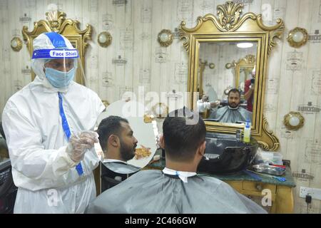 Dhaka, Bangladesh. 23rd June, 2020. A hairdresser in protective suit shows a small mirror to a customer as he can see his hair style at a salon during the COVID-19 pandemic in Dhaka, Bangladesh, June 23, 2020. Credit: Str/Xinhua/Alamy Live News Stock Photo