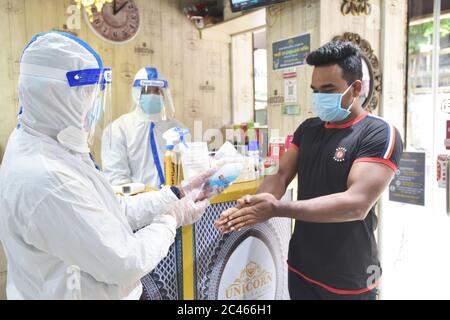 Dhaka, Bangladesh. 23rd June, 2020. A staff member in protective suit sanitizes hands for a customer at a salon during the COVID-19 pandemic in Dhaka, Bangladesh, June 23, 2020. Credit: Str/Xinhua/Alamy Live News Stock Photo