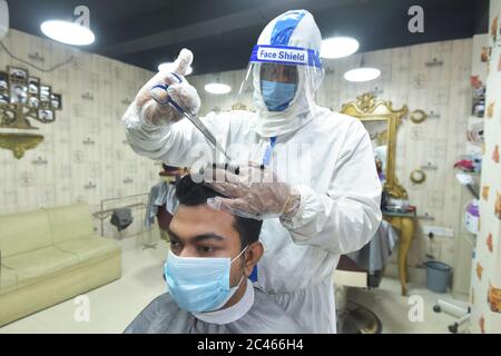 Dhaka, Bangladesh. 23rd June, 2020. A hairdresser in protective suit cuts hair for a customer at a salon during the COVID-19 pandemic in Dhaka, Bangladesh, June 23, 2020. Credit: Str/Xinhua/Alamy Live News Stock Photo