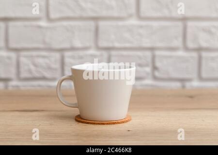 White ceramic cup for coffee on cork coaster on wooden table isolated on white Stock Photo