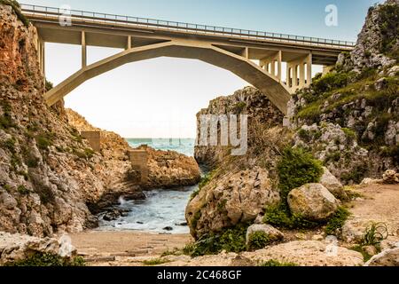 The Ciolo bridge connects two high cliffs. An inlet of the sea, in Gagliano del Capo, near Santa Maria di Leuca. The red and orange sunset. On a winte Stock Photo