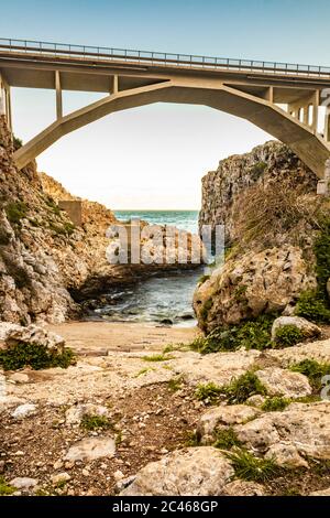 The Ciolo bridge connects two high cliffs. An inlet of the sea, in Gagliano del Capo, near Santa Maria di Leuca. The red and orange sunset. On a winte Stock Photo