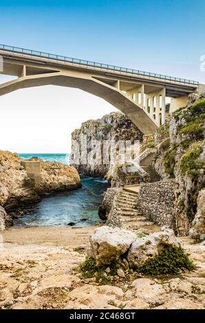 The Ciolo bridge connects two high cliffs. An inlet of the sea, in Gagliano del Capo, near Santa Maria di Leuca. The red and orange sunset. On a winte Stock Photo