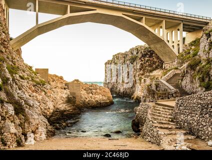 The Ciolo bridge connects two high cliffs. An inlet of the sea, in Gagliano del Capo, near Santa Maria di Leuca. The red and orange sunset. On a winte Stock Photo