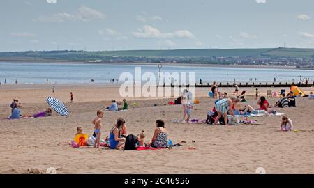 Portobello, Edinburgh, Scotland, UK. 24 June 2020. The hot weather brought families out but the seaside was not overly busy, plenty room to keep a social distance on the beach and promenade. People out on various paddle boards and inflatables and others having picnics on the sandy beach. Stock Photo