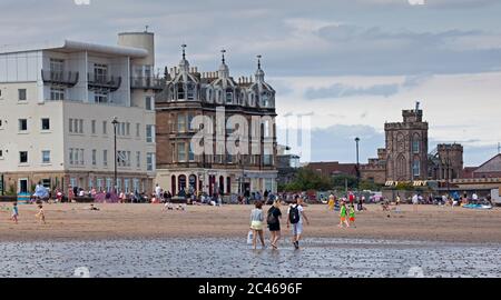 Portobello, Edinburgh, Scotland, UK. 24 June 2020. The hot weather brought families out but the seaside was not overly busy, plenty room to keep a social distance on the beach and promenade. People out on various paddle boards and inflatables and others having picnics on the sandy beach. Stock Photo