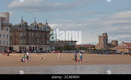 Portobello, Edinburgh, Scotland, UK. 24 June 2020. The hot weather brought families out but the seaside was not overly busy, plenty room to keep a social distance on the beach and promenade. People out on various paddle boards and inflatables and others having picnics on the sandy beach. Stock Photo