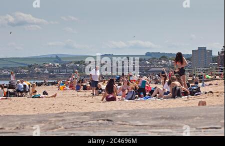 Portobello, Edinburgh, Scotland, UK. 24 June 2020. The hot weather brought families out but the seaside was not overly busy, plenty room to keep a social distance on the beach and promenade. People out on various paddle boards and inflatables and others having picnics on the sandy beach. Stock Photo