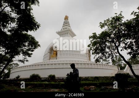 A student walking on a walkway in front of the Vishwa Shanti Stupa (World Peace Pagoda) in Rajgir, Bihar, India. Stock Photo