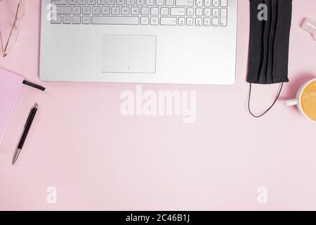 Flat lay composition with medical mask laptop, coffee, notebook on pink background. Stock Photo
