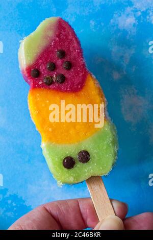 Rowntrees Fruit Stack ice lolly unwrapped set on blue patterned background - Apple, orange and strawberry fruit ice with chocolate flavoured pieces Stock Photo