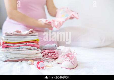 A pregnant woman is folding baby things. Selective focus. people. Stock Photo