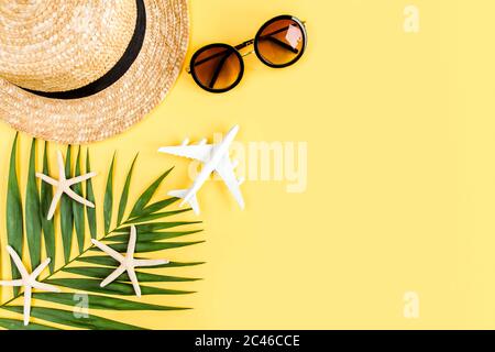 Traveler accessories concept on yellow background. model plane, airplane, straw hat and tropical palm leaf.  Stock Photo