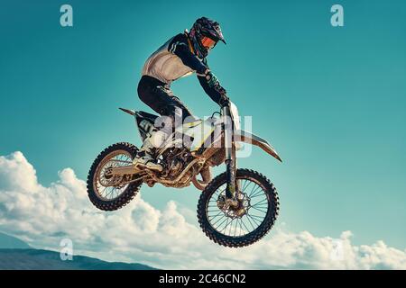 racer on mountain bike participates in motocross race, takes off and jumps on springboard, against the blue sky. Close-up. concept of extreme rest Stock Photo