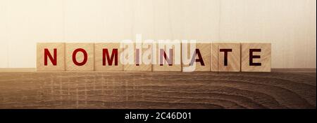 Nominate word on wooden cubes. Concept of words to put forward a candidat for voting or election Stock Photo
