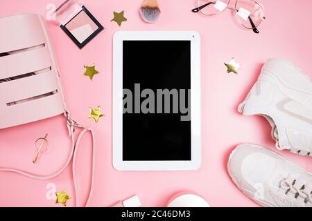 Tablet mock-up on the pink background with feminine outfit and make-up, top view. Stock Photo