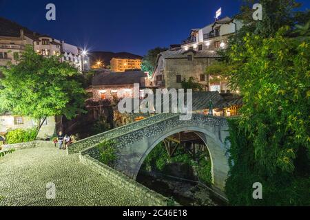 MOSTAR, BOSNIA AND HERZEGOVINA -  14TH AUGUST 2016: A view of the Kriva Cuprija/ Crooked Bridge in Mostar at night. Other buildings can be seen. Stock Photo