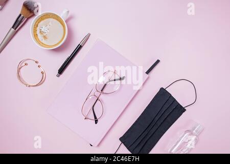 Flat lay composition with medical mask laptop, coffee, notebook on pink background. Stock Photo