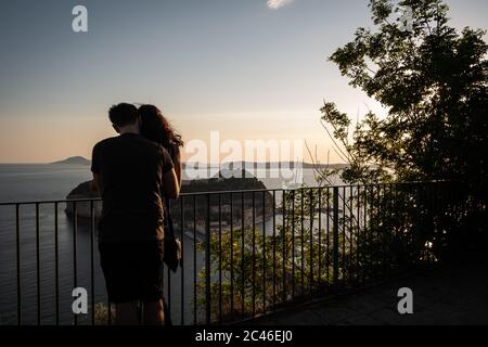 Naples, Italy. 23rd June, 2020. NAPLES, ITALY - JUNE 23 - A couple watch the sunset from the viewpoint of the Virgilian Park of Posillipo in Naples, June 23, 2020. Credit: Manuel Dorati/ZUMA Wire/Alamy Live News Stock Photo