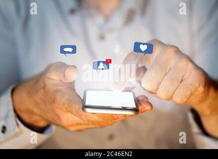 Close up of teenager or adult man on social media sending text on smartphone with social network notification icons of like, message, love and friends Stock Photo