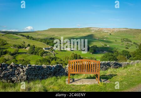 A seat with a view. Wooden bench overlooking Arkengarthdale in Swaledale,North Yorkshire. Summertime in the Yorkshire Dales with blue sky green fields Stock Photo