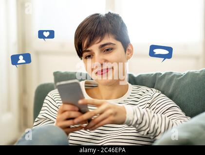 Woman using smart phone with social media or social network notification icons of like, comment, follow me and friend me in Social media marketing and Stock Photo