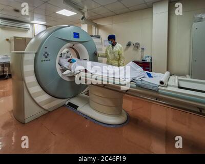 Computed Tomography machine (CT) in Radiology Department with radiology technician wearing personal protective equipment  preparing COVID-19 patient Stock Photo