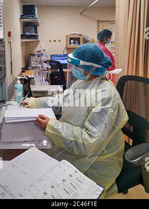 Nurse wearing PPE mask and gloves talking to patient Stock Photo - Alamy