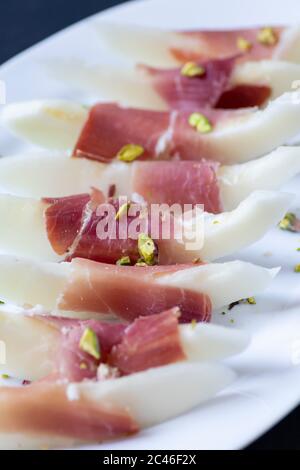 Still life with fresh melon, jamon and red wine on the table. Photo in ...