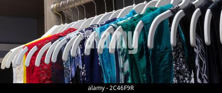 Women's colorful wardrobe on hangers in ordered row Stock Photo