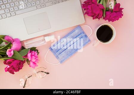 Flat lay composition with medical mask laptop, coffee, notebook on pink background. Stock Photo