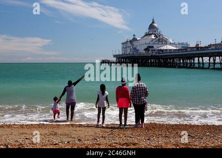 Beach and pier with family standing on water edge, Eastbourne, East Sussex, England, United Kingdom, Europe Stock Photo